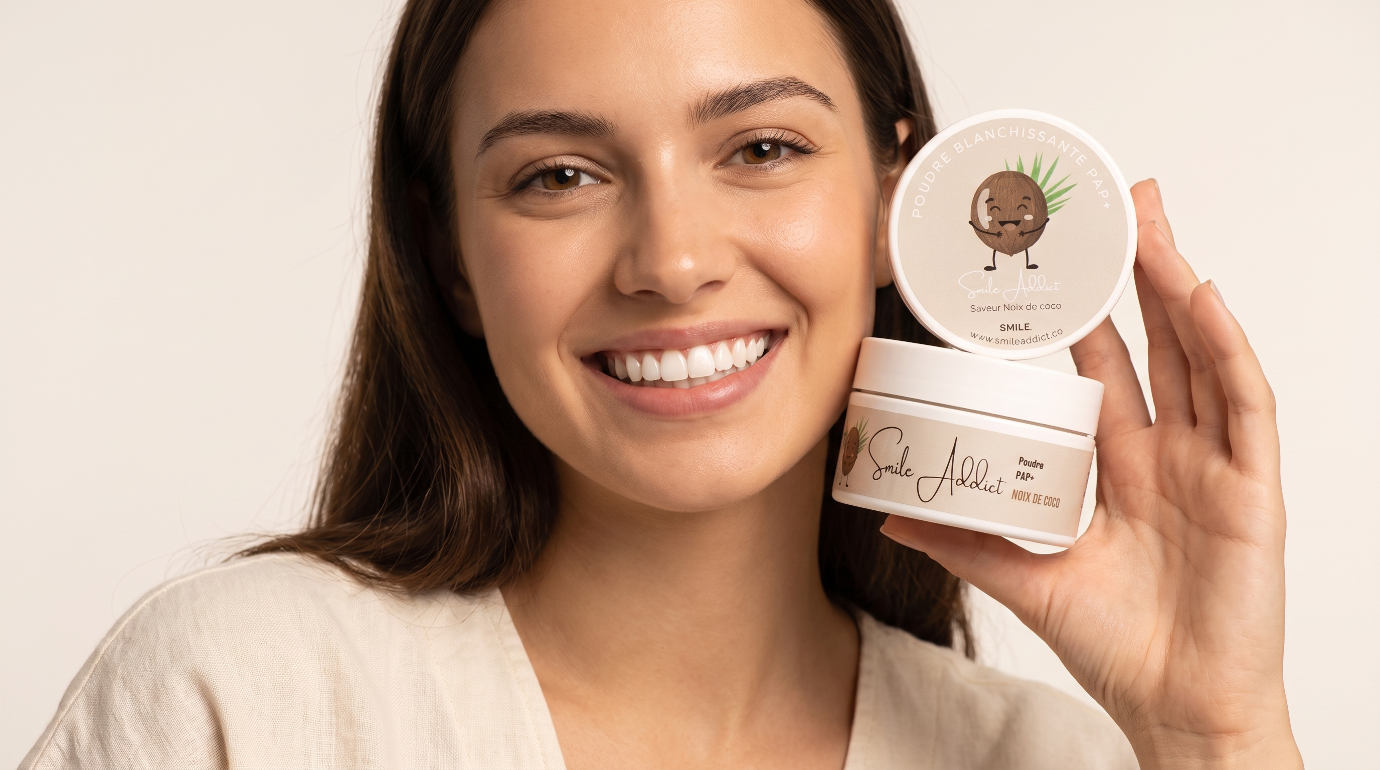 Femme souriante tenant la poudre blanchissante Smile Addict saveur noix de coco, solution de blanchiment dentaire a domicile